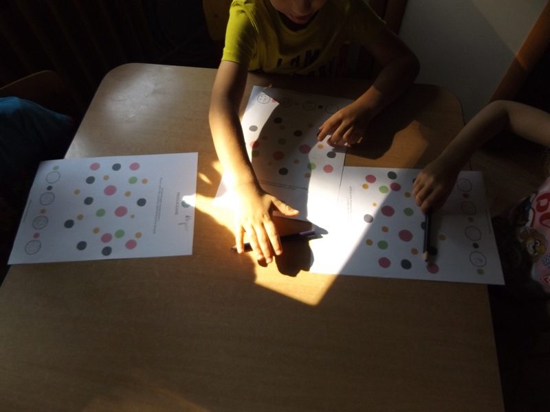 Sala przedszkolna. Przy stoliku dwoje dzieci w trakcie tworzenia rysunku. Na stoliku trzy kartki z kolorowymi kropkami.