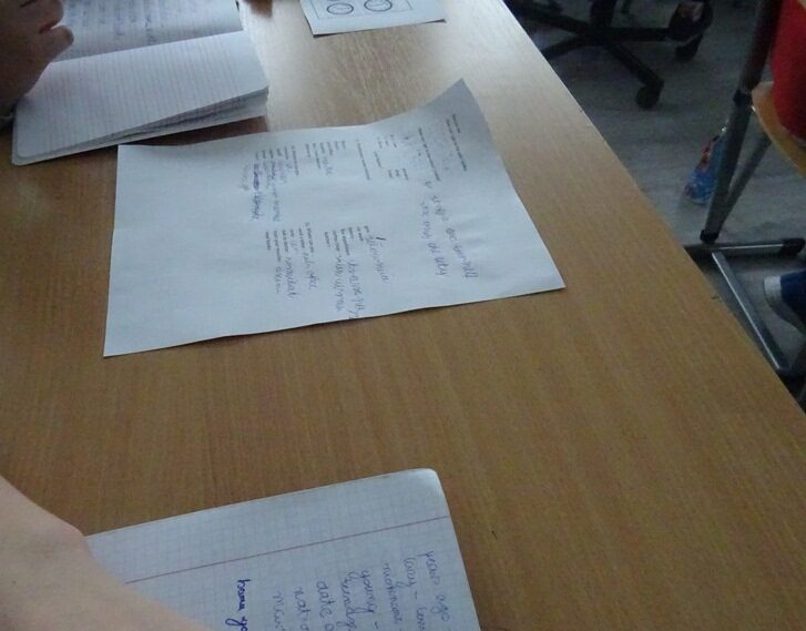 Sala lekcyjna. Na stoliku leżą kartki z informacjami dotyczącymi nauki języka angioelskiego.