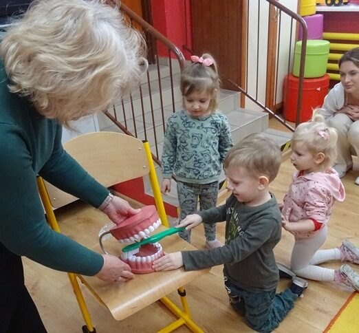 Sala przedszkolna. Dzieci szczotkują zęby na modelu szczęki.