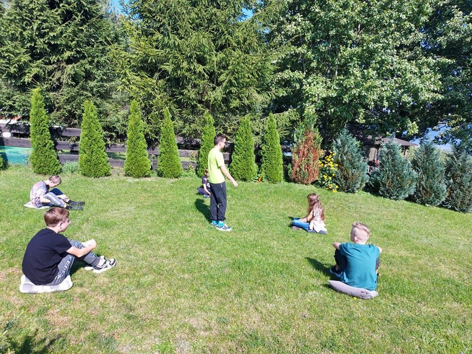 Uczniowie na trawniku podczas zabawy terenowej.