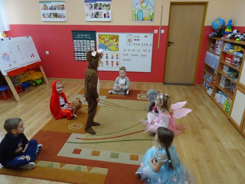 Sala przedszkolna. Dzieci w przebraniach siedzą na dywanie.