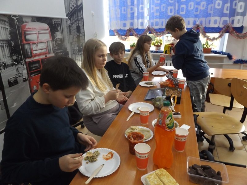 Sala lekcyjna. Uczniowie siedzą przy stolikach i jedzą.