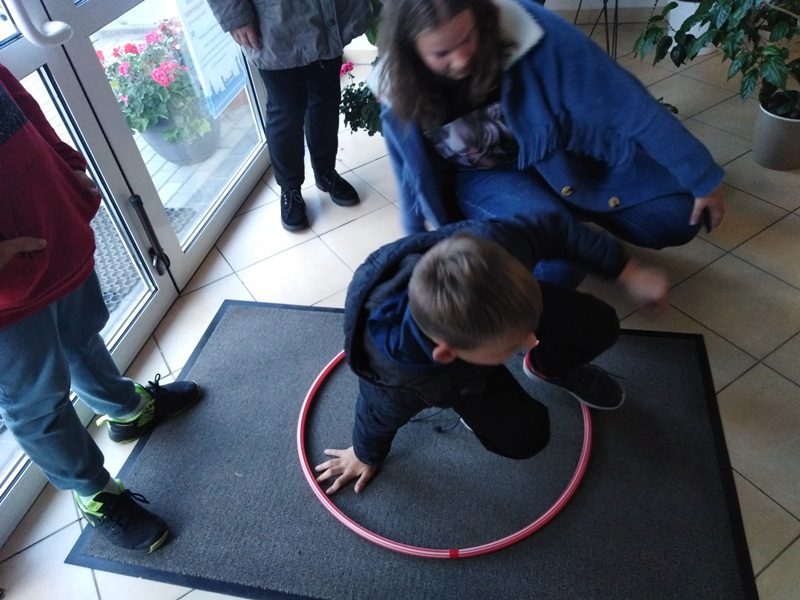 W bibliotece w Olecku. Uczniowie wykonują zadanie z obręczą na podłodze.