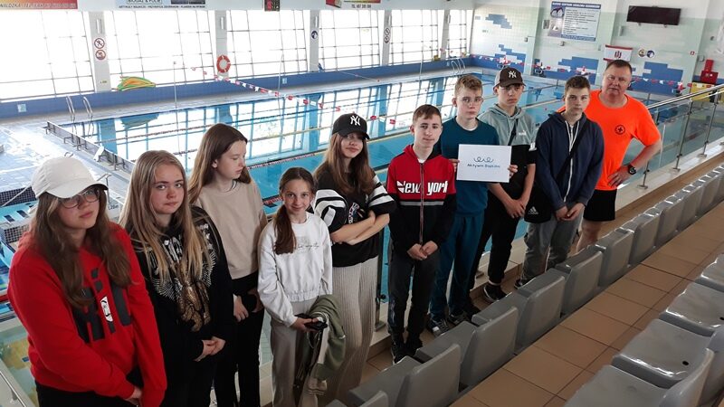 Hala Lega w Olecku. Uczniowie i ratownik wodny stoją przy basenie.