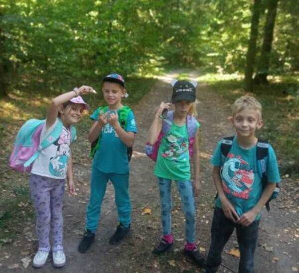 Las w Judzikach. 4 uczniów stoi na leśnej drodze.