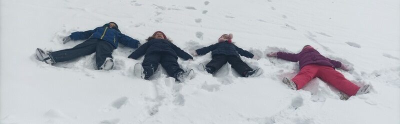 Posesja szkolna. Dzieci leżą na śniegu.