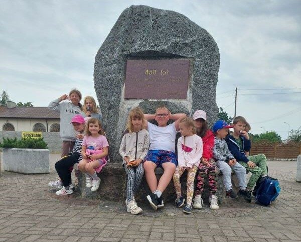 Safari. Dzieci siedzą przed pomnikiem z kamienia.