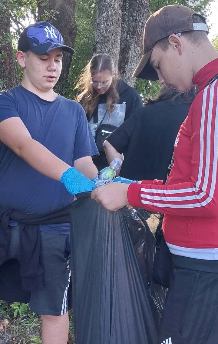 Posesja szkolna. Uczniowie trzymają worek ze śmieciami.